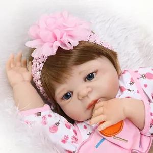 Bambola reborn realistica con tutina a fiori rosa e fascia floreale su tappeto di peluche