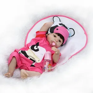 Bambola reborn realistica con vestito da mucca rosa, ciuccio e biberon su tappeto
