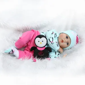 Poupée bébé Reborn réaliste en tenue de pingouin bleu sur un tapis en peluche blanc