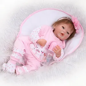 Realistic reborn baby doll with brown hair and pink cat outfit on soft white background