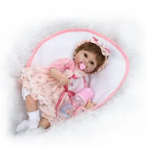 Realistic reborn baby doll in pink floral dress with pacifier and feeding bottle