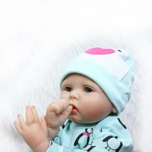 Poupée réaliste bébé reborn avec tenue pingouin bleu et bonnet sur fond en peluche