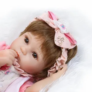 Lifelike baby doll with floral headband and pink outfit on white plush background