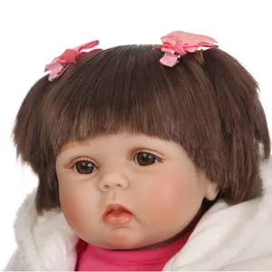 Poupée bébé reborn réaliste avec cheveux bruns, nœuds roses et peluche blanche