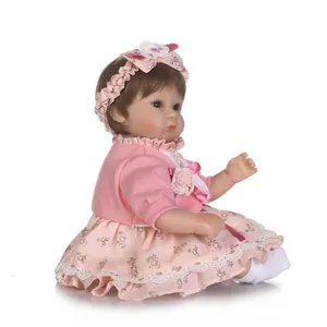 Realistic reborn baby doll with pink floral lace dress and headband on white background