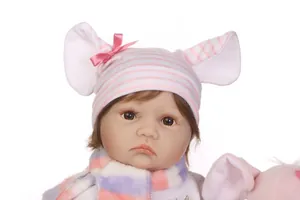 Nahaufnahme einer Reborn-Puppe mit rosa Tierohrenmütze und lila Plüsch-Halstuch
