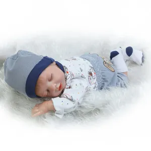Realistic reborn baby doll sleeping in blue striped outfit on white plush rug