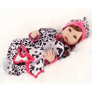 Lifelike reborn baby doll in cow print outfit with plush toy on white faux fur rug
