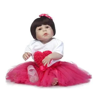Realistic reborn baby doll with brown hair, pink tutu dress and feeding bottle toy