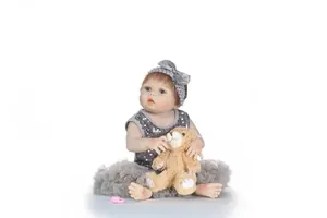Détail de poupée Reborn avec cheveux bruns, yeux bleus, tutu et ours en peluche
