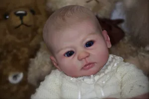 Poupée Reborn réaliste aux yeux bleus et cheveux peints avec un pull en tricot blanc