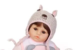 Detailed close-up of a realistic reborn baby doll with brown hair and knit animal hat