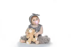 Gros plan d'une poupée reborn réaliste en robe grise à paillettes avec ours et sucette
