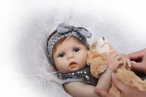 Gros plan d'une poupée bébé réaliste avec peau douce, yeux bleus et un ours en peluche