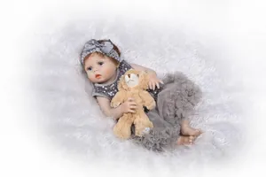 Détail de poupée Reborn en robe à paillettes grises et bandeau avec ours en peluche