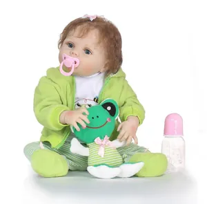 Détail d'une poupée reborn avec tenue en polaire verte et peluche de grenouille