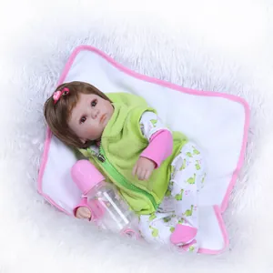 Lifelike reborn baby doll with green fleece vest and accessories on soft white plush