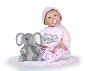 Détail de poupée réaliste avec éléphant en peluche et tenue à pois rose et blanc