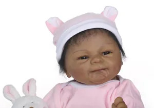Gros plan de poupée Reborn à la peau foncée en tenue rose et blanche avec lapin en peluche