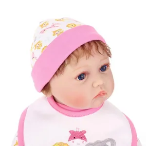 Realistic reborn baby doll with cartoon animal print hat and bib set on white background