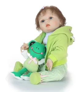 Détail de la poupée Reborn réaliste avec boucles brunes tenant une peluche grenouille verte