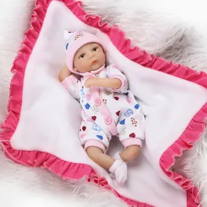 Miniature realistic reborn baby doll wearing a pink heart-patterned romper and a hat