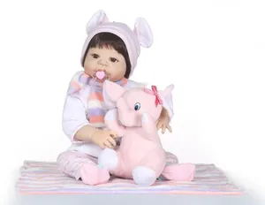 Close-up of lifelike newborn doll with pink knit hat and plush elephant toy