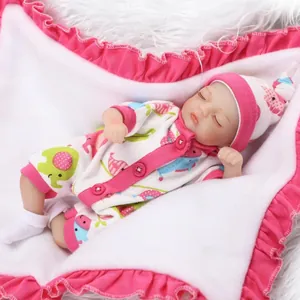 Miniature reborn baby doll in floral elephant outfit sleeping on plush background