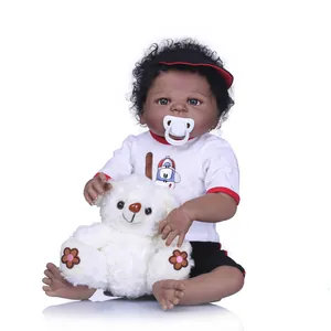 Realistic African reborn baby doll with curly hair, red hat, and white plush bear toy