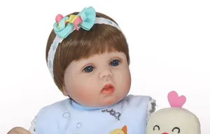 Close-up of lifelike baby doll with blue eyes, brown hair and a cute blue bib
