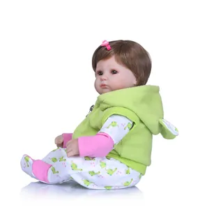 Realistic reborn baby doll with brown hair and green dinosaur fleece outfit