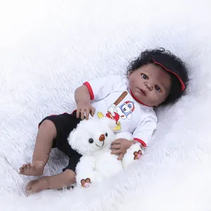 Realistic black baby doll with curly hair wearing a red baseball outfit and plush bear