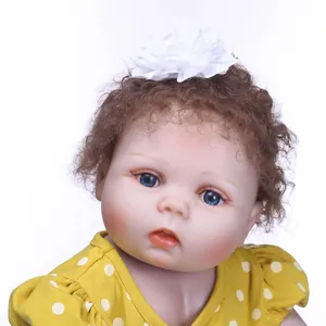 Realistic reborn baby doll with curly brown hair and yellow polka dot dress