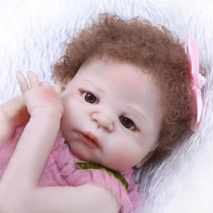 Bambola reborn realistica con capelli ricci castani e vestito di pizzo rosa su peluche