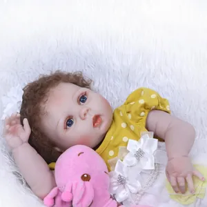 Realistic reborn baby doll in yellow polka dot dress with pink plush toy on white rug
