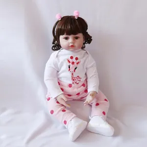 Realistic reborn baby doll with brown hair and giraffe embroidery jumpsuit in sitting pose
