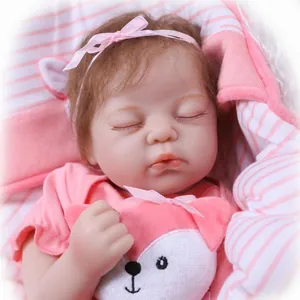 Lifelike sleeping reborn baby doll with pink bow headband and soft striped blanket