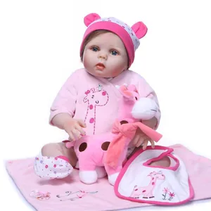 Lifelike reborn baby doll in pink velvet outfit with giraffe plush toy and accessories