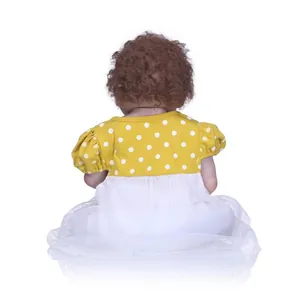 Rear view of lifelike reborn baby doll with brown curls and yellow polka dot dress