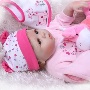 Close-up of reborn baby doll with blue eyes, pink floral hat, and giraffe bib accessory
