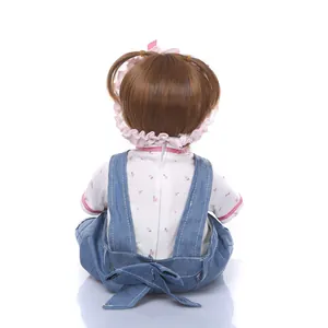 Vue arrière de poupée reborn réaliste en salopette denim et chemise à fleurs avec nœuds