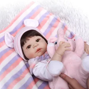 Lifelike reborn baby doll with dark hair and pink elephant toy on a striped blanket