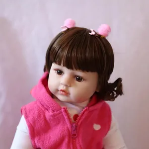 Lifelike 60cm reborn baby doll with brown hair, pink fleece vest and hair clips