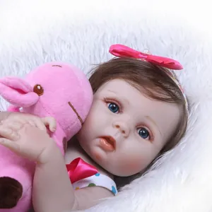 Detailed close-up of a lifelike reborn baby doll with brown hair and pink hippo plush toy
