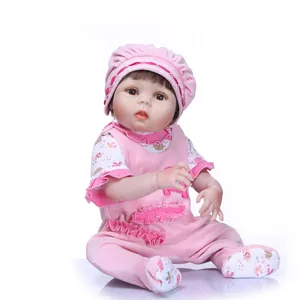 Realistic reborn baby doll in pink floral outfit and matching hat on white background