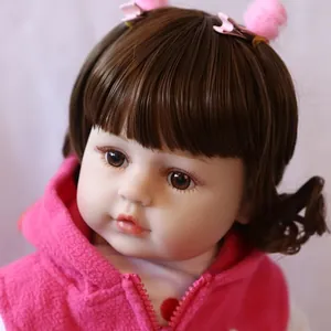 Lifelike reborn doll with brown hair and pink fleece hoodie in a close-up front view