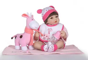 Detailed set of realistic reborn baby doll with giraffe plush toy and pink accessories