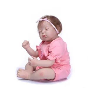 Lifelike reborn baby doll in pink cotton romper with headband on white background