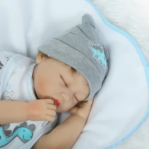 Bambola Reborn realistica con vestito da dinosauro blu e cappello su tappeto morbido