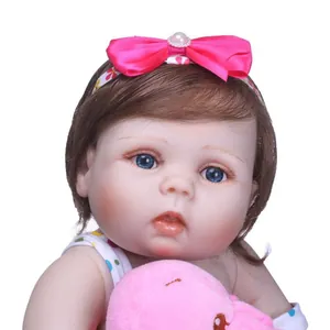 Close-up of lifelike baby doll with blue eyes, brown hair and floral headband accessory